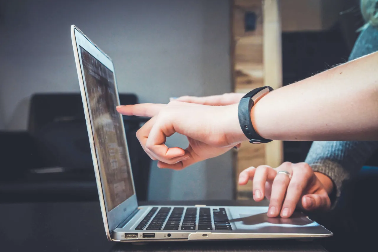 Een vinger wijst naar een website op een laptop