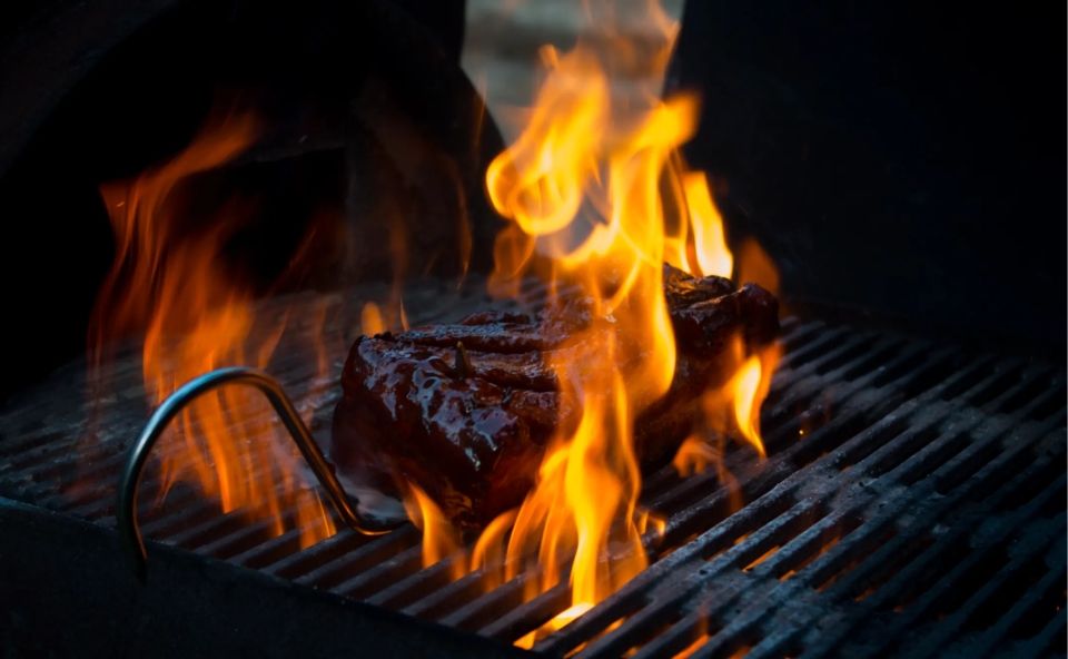 Een stuk vlees tussen hoge vlammen op een BBQ